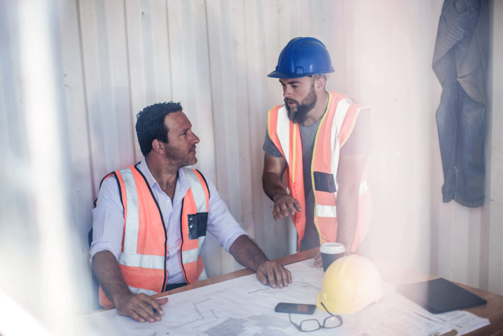 Construction foreman and builder meeting at desk in portable cabin