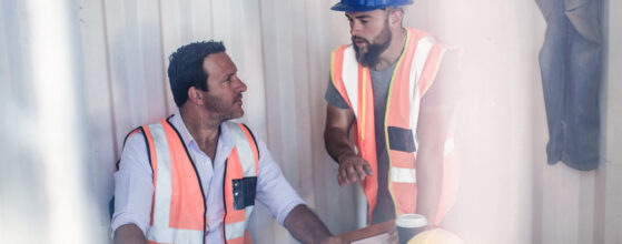 Construction foreman and builder meeting at desk in portable cabin