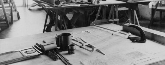 Architectural drafting table with blueprints and drawing instruments laid out
