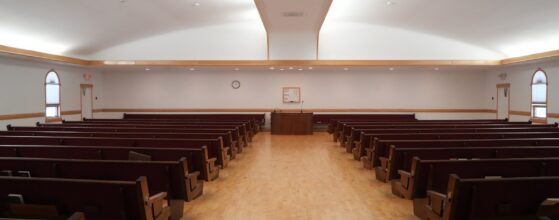 Rows of empty wooden pews in a bright church interior