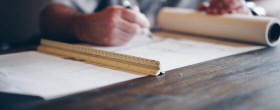 Architect drafting building design drawings on a blueprint at a table