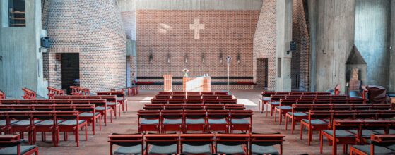 Rows of empty chairs inside a modern church sanctuary