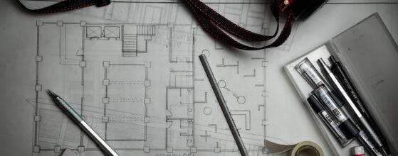 Construction blueprints with drafting pencils and a metal ruler on a table