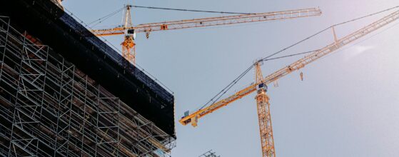 Yellow tower crane beside a commercial building under construction in daylight