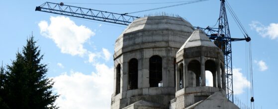 Church building under construction with a crane against a blue sky