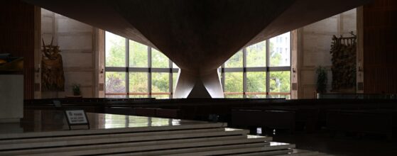 Modern church sanctuary interior with tall daylit windows behind the altar