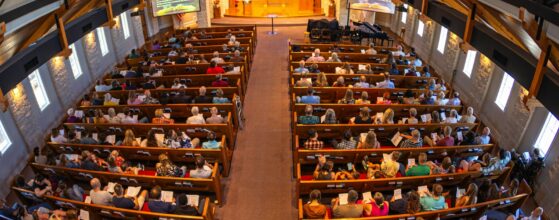 Full congregation seated in a modern church sanctuary viewed from the balcony