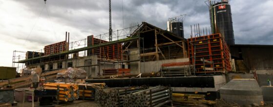Concrete building construction site with formwork, scaffolding, and a tower crane
