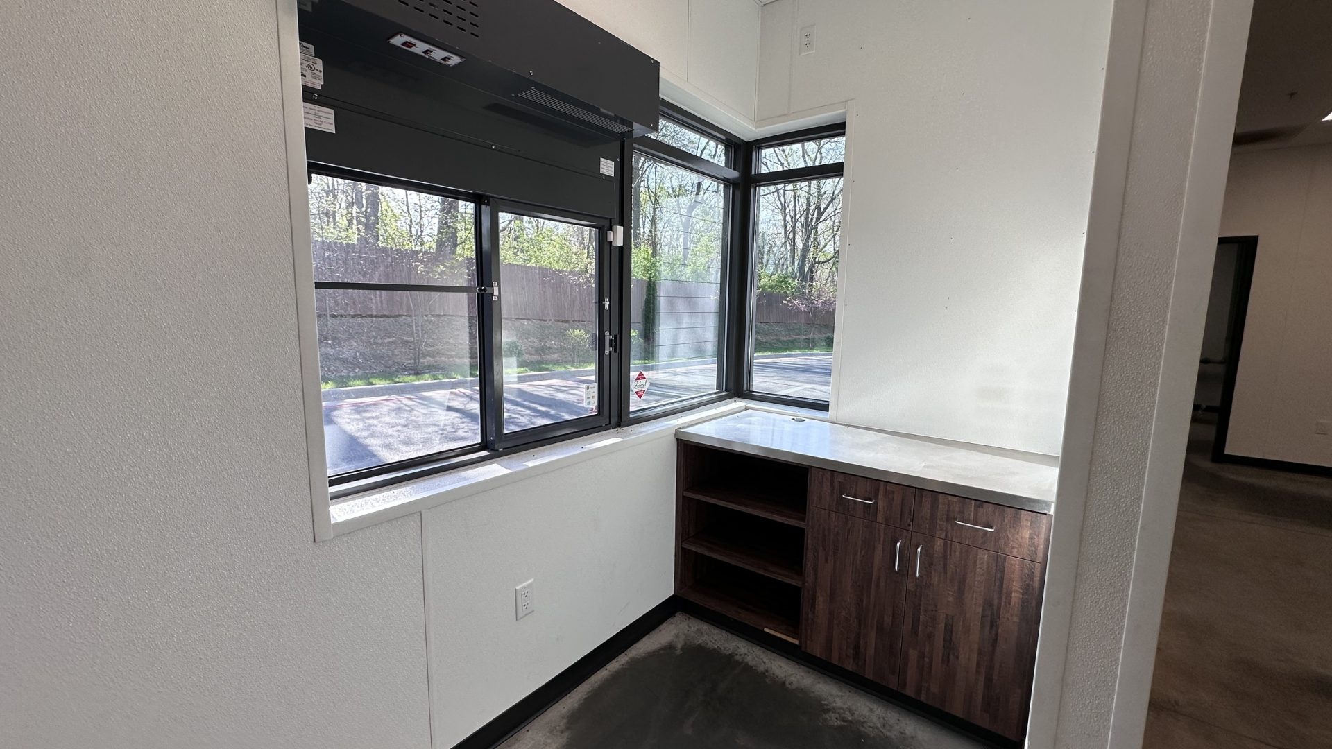 Interior corner with windows, built-in wood cabinets and metal countertop in an unfinished commercial space