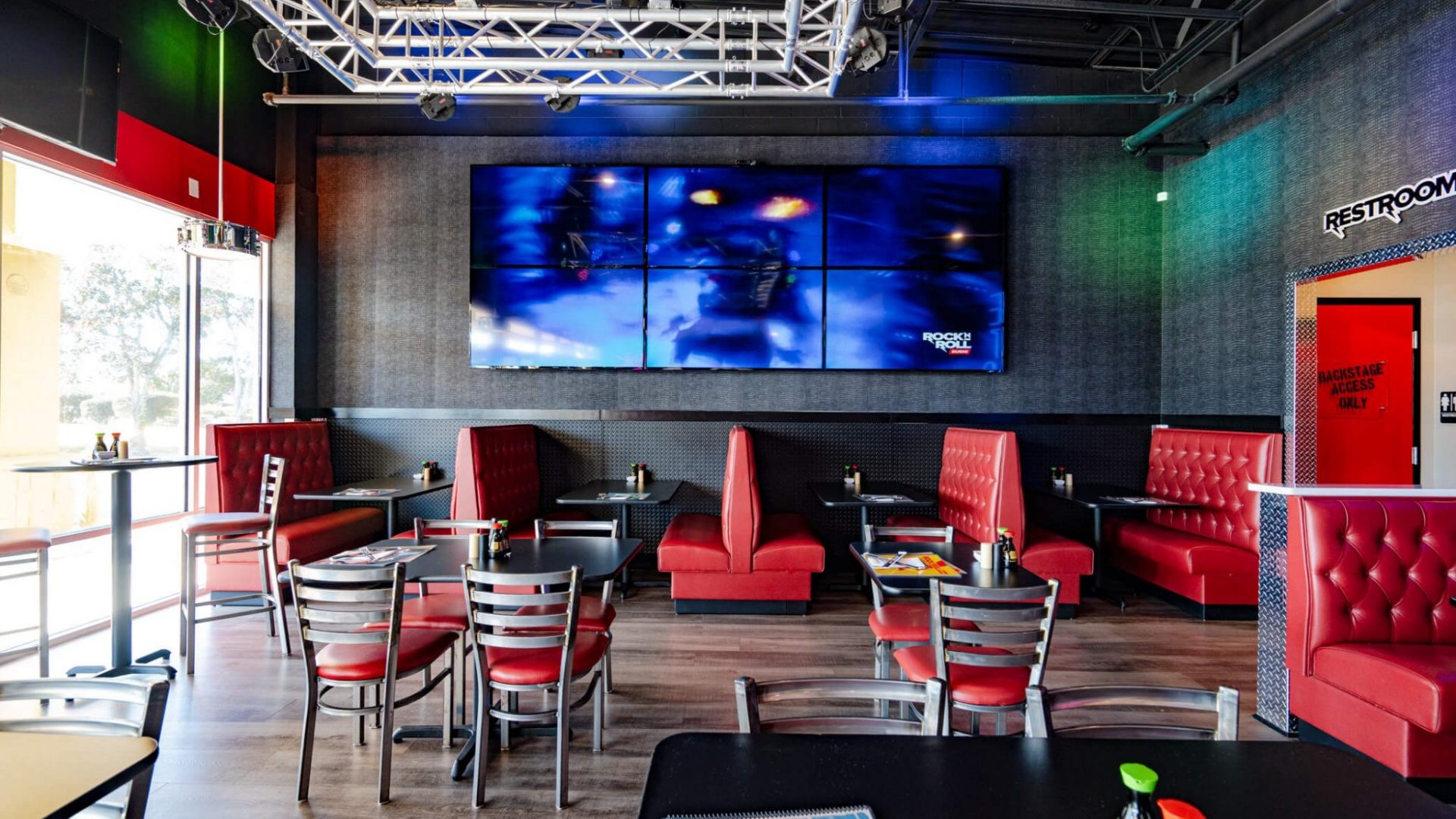 Dining room of Rock N Roll Sushi with red booths and video wall